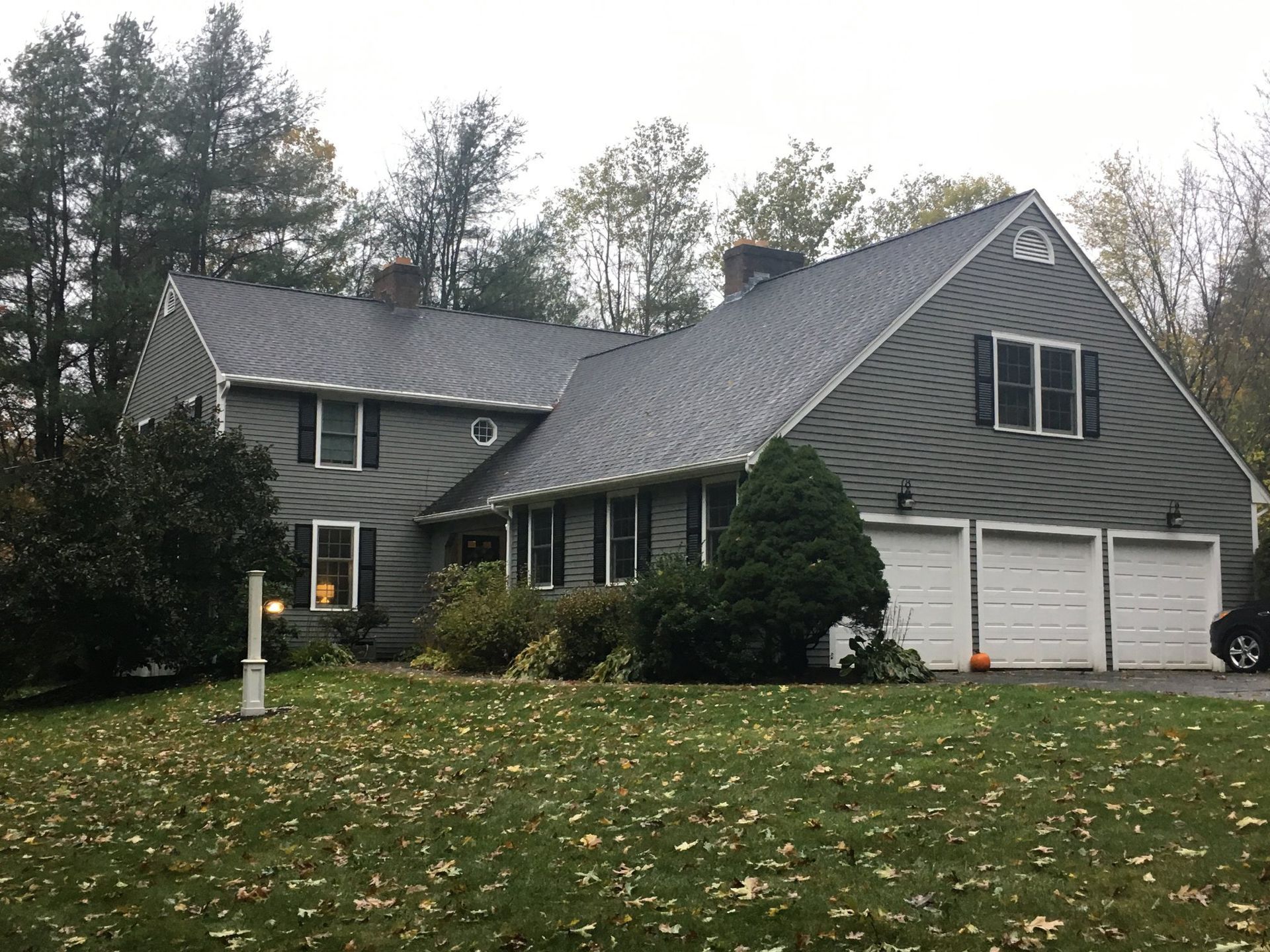A large house with a gray roof and white garage doors