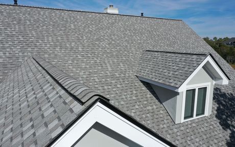 An aerial view of a house with a gray roof and a window.