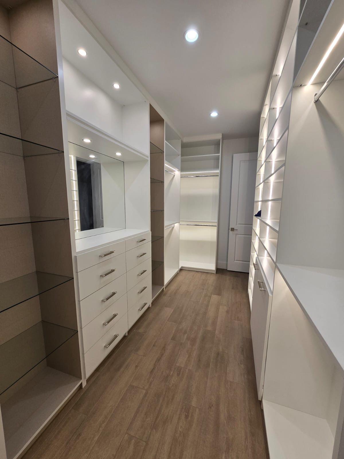 A walk in closet with lots of shelves and drawers.