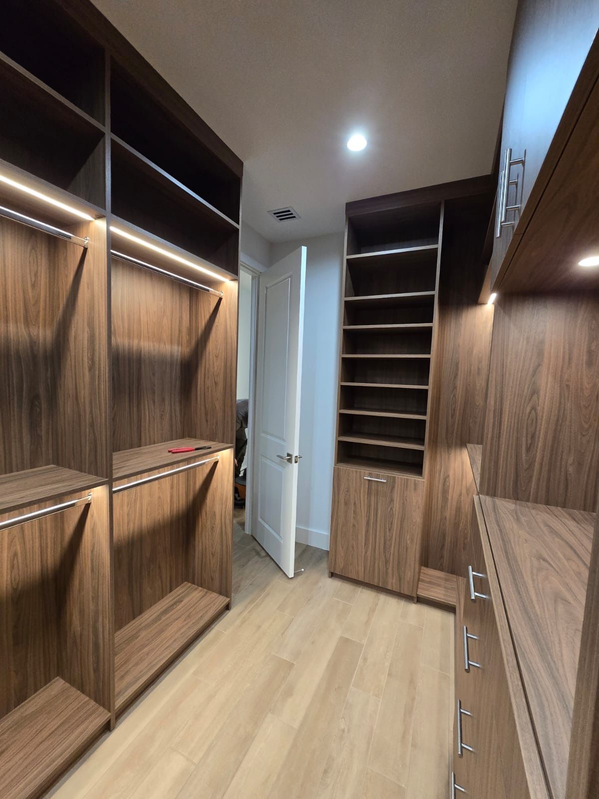 A walk in closet with wooden shelves and cabinets.