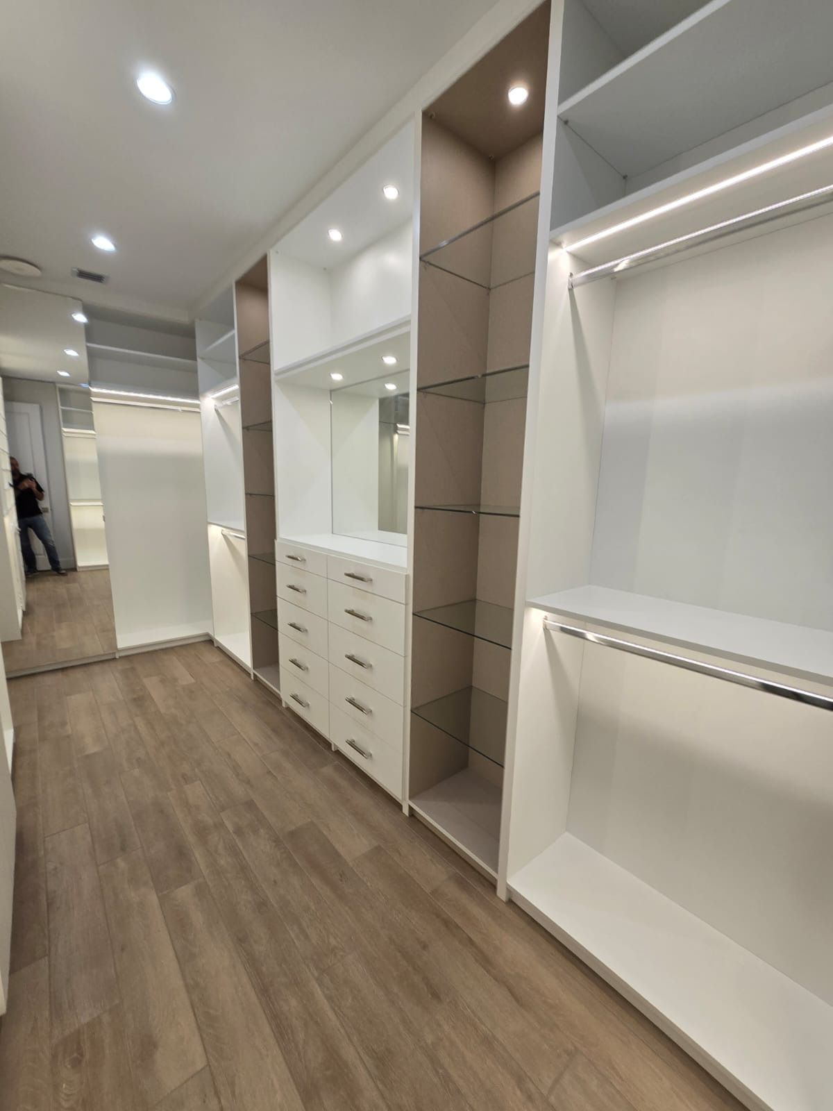 A walk in closet with lots of shelves and drawers and a mirror.