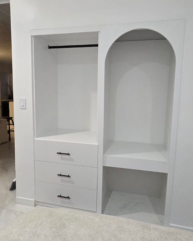 A white closet with drawers and a shelf in a room.