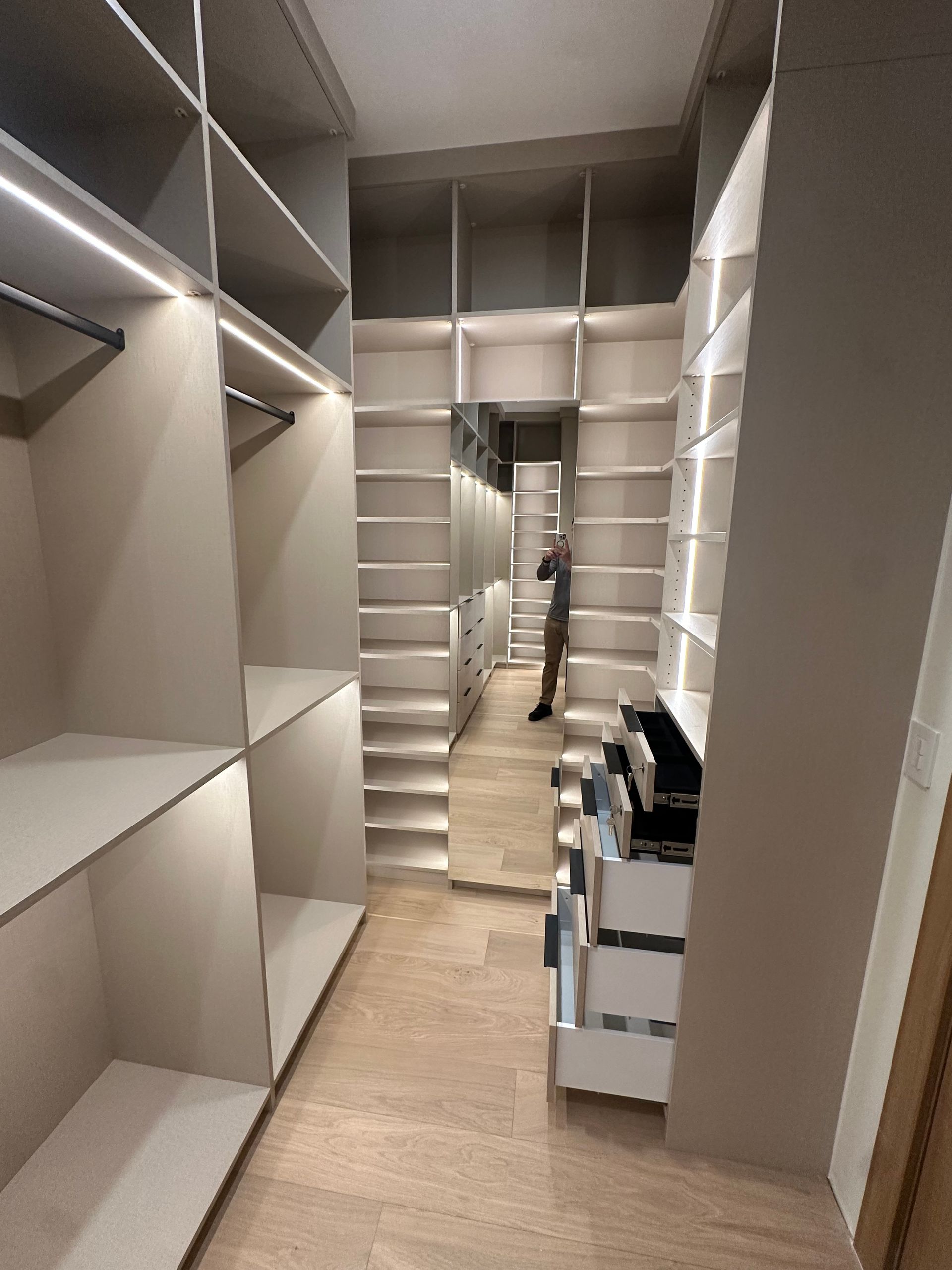 A walk in closet with lots of shelves and drawers