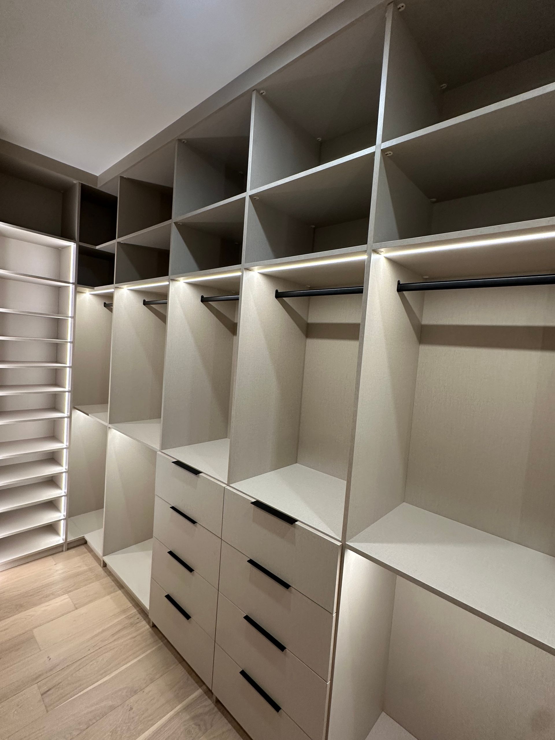 A walk in closet with lots of shelves and drawers