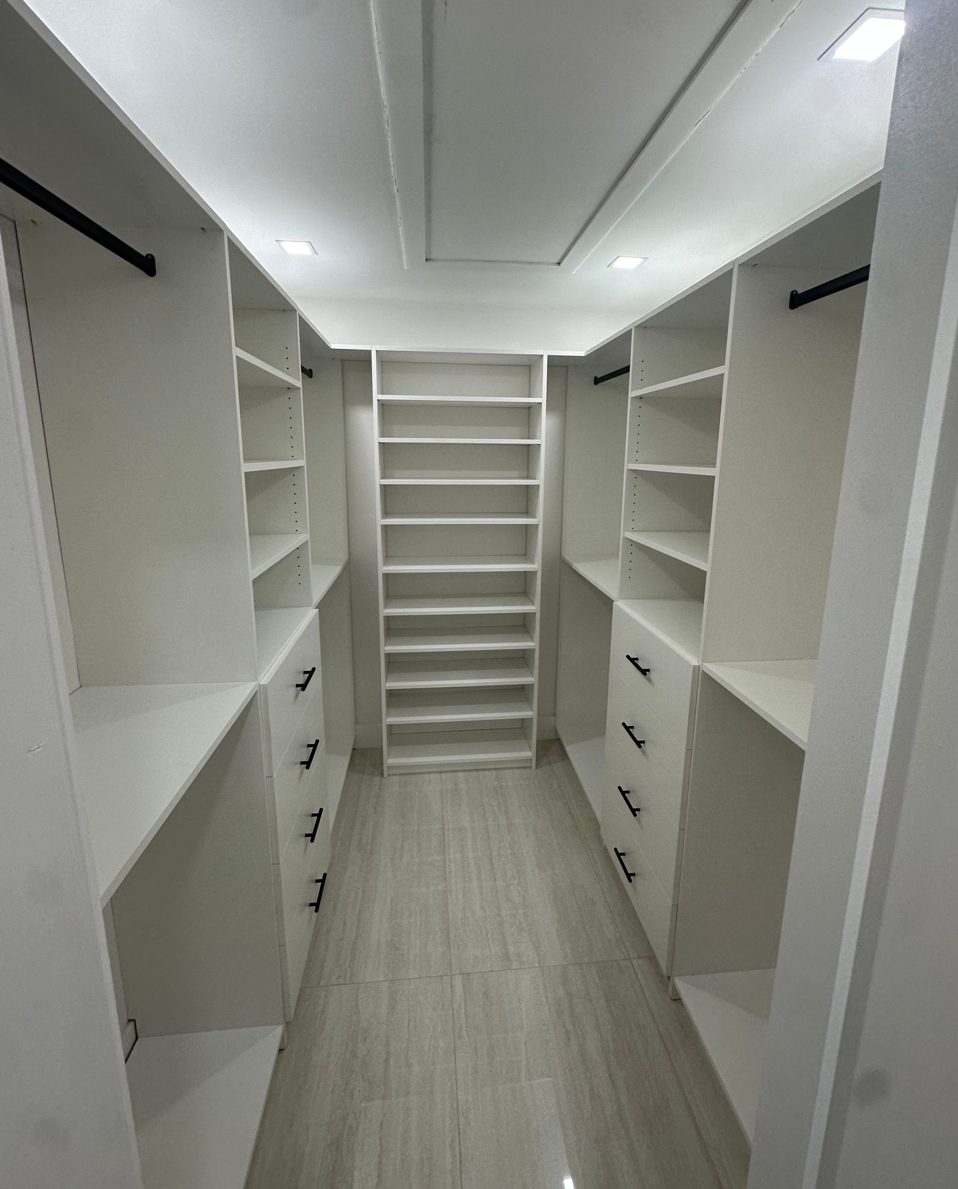 A walk in closet with lots of shelves and drawers.