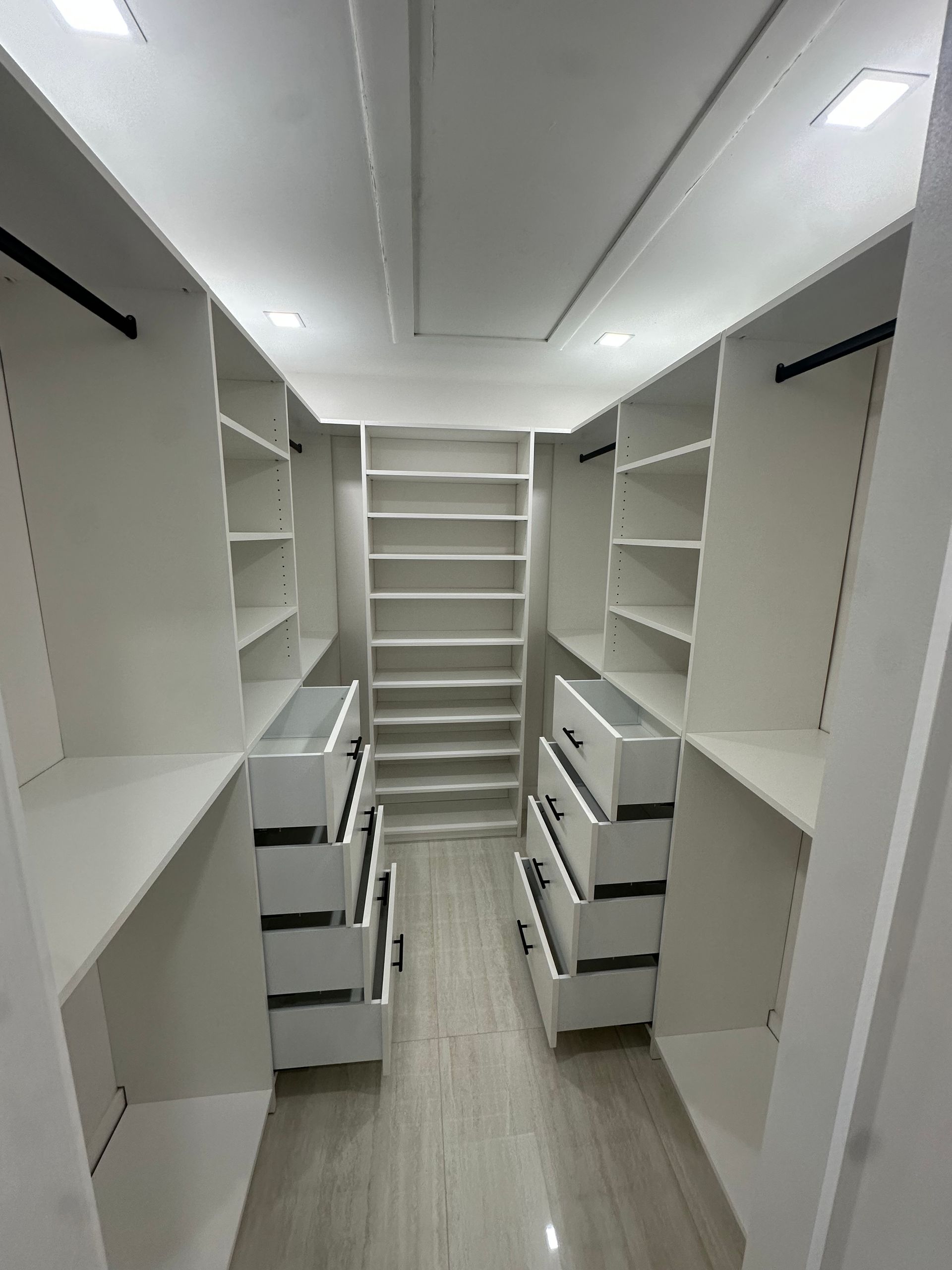 A walk in closet with lots of shelves and drawers.