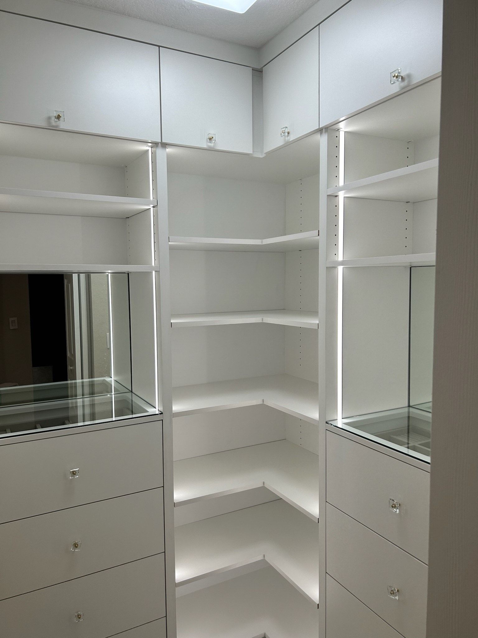 A walk in closet with lots of shelves and drawers