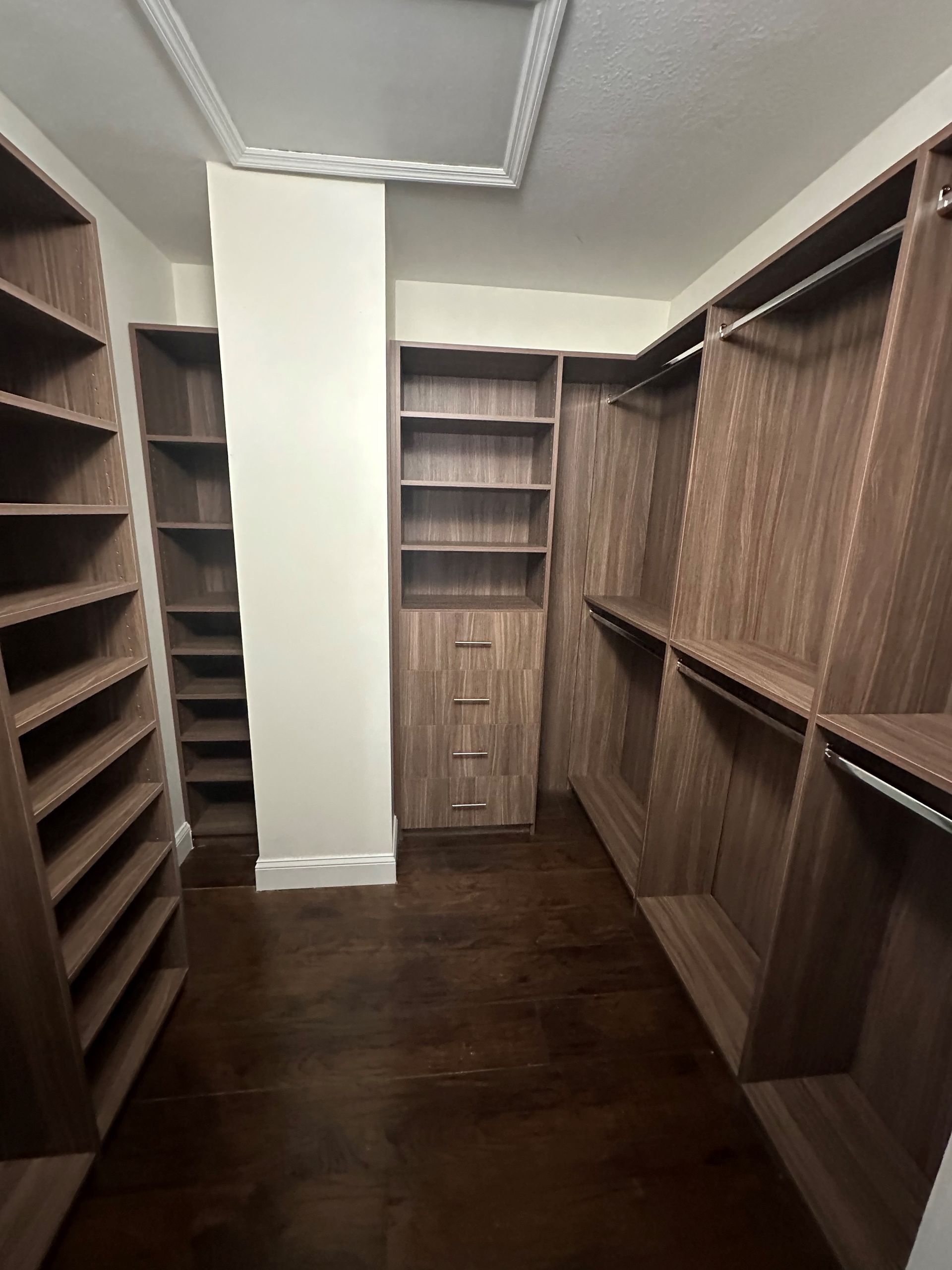 A walk in closet with lots of shelves and drawers