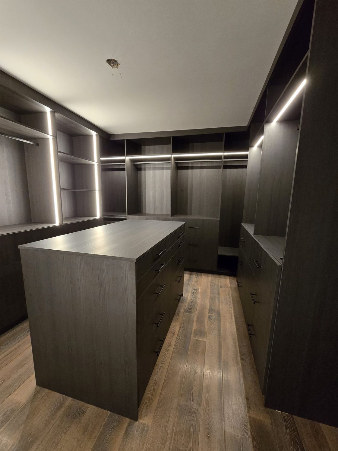 A large walk in closet with a large island in the middle.