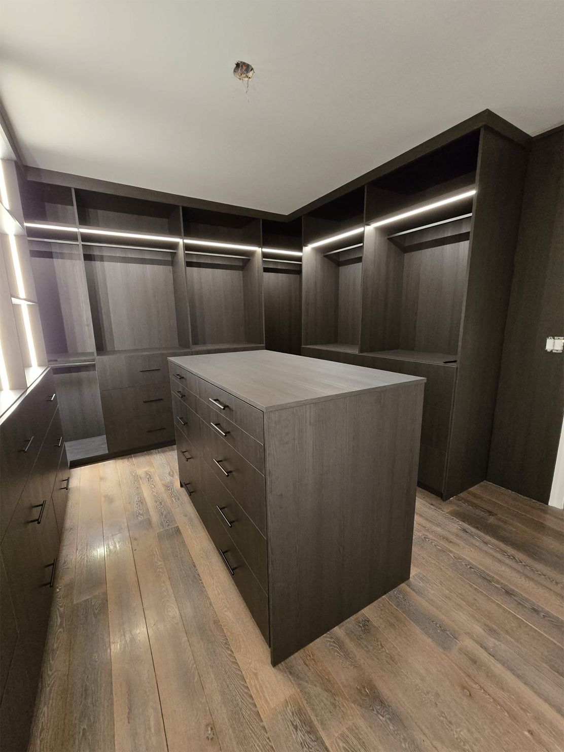A walk in closet with a large island in the middle.