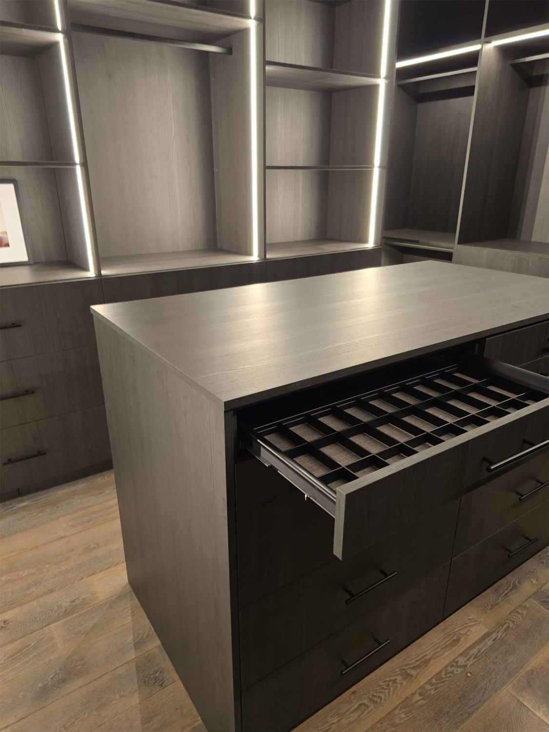 A walk in closet with a large island in the middle.