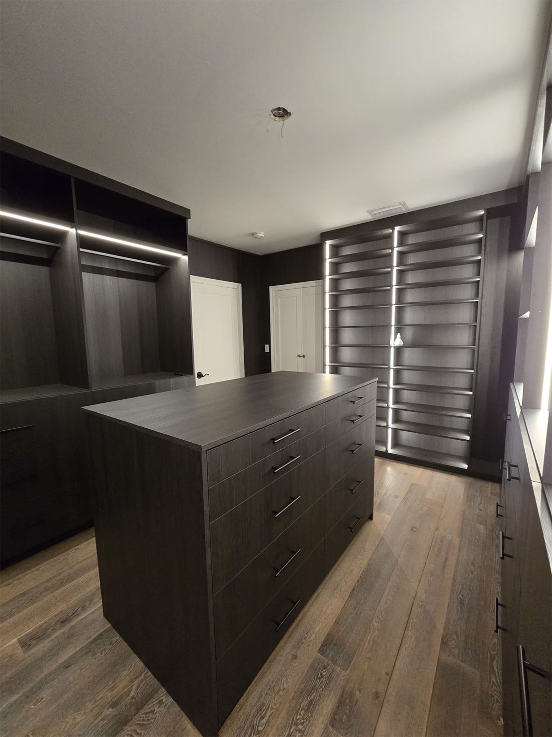 A walk in closet with a large island in the middle.