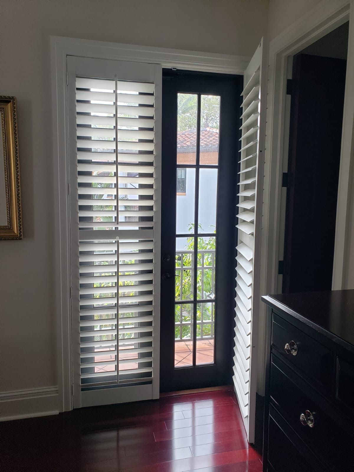 a room with a black door and white shutters
