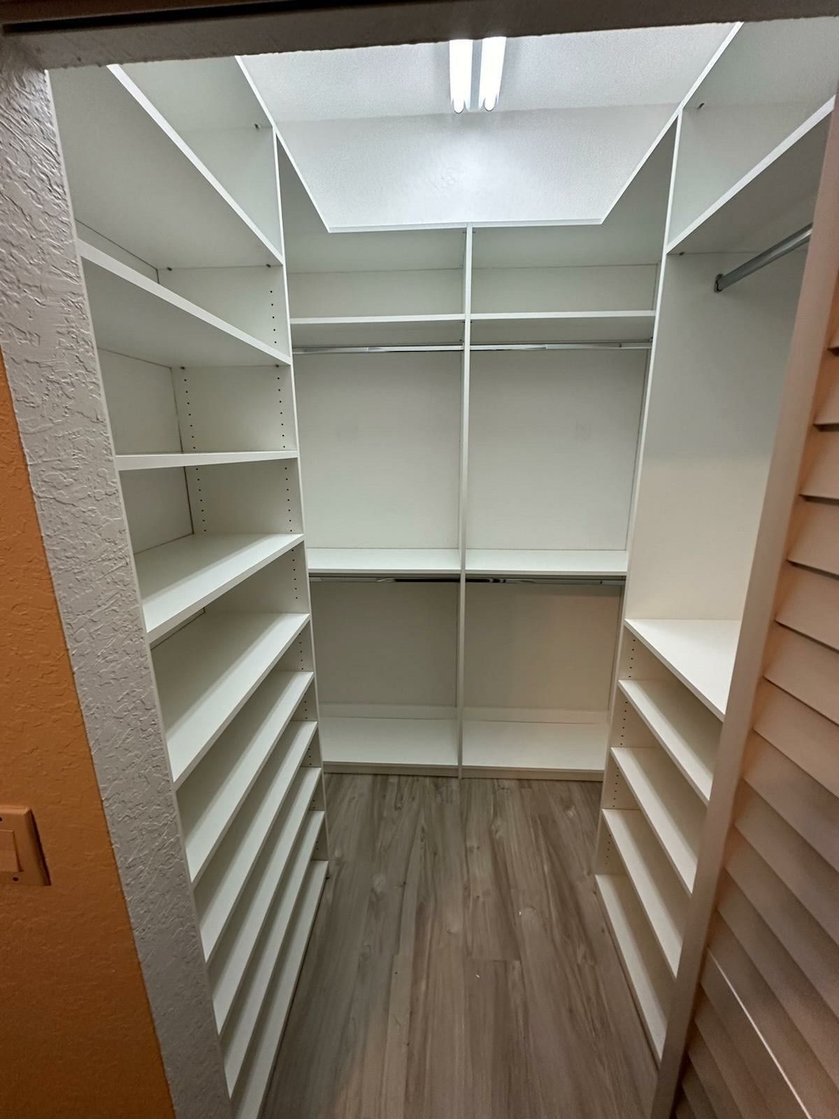 A walk in closet with lots of shelves and a wooden floor.
