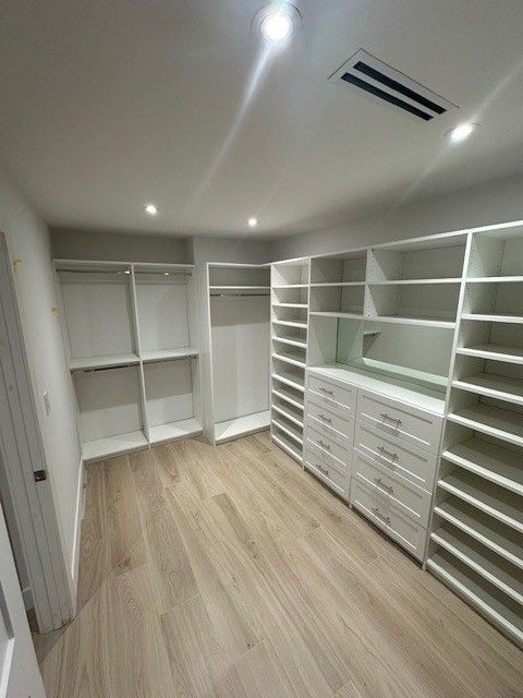 A walk in closet with lots of shelves and drawers.