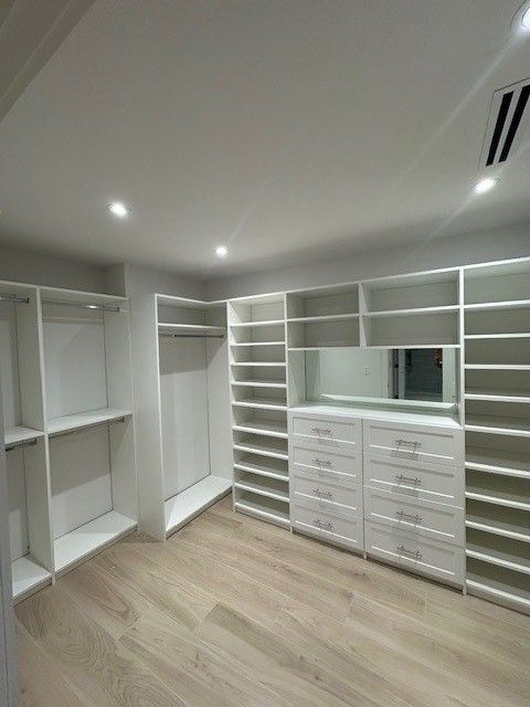 A walk in closet with lots of shelves and drawers and a mirror.