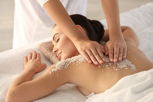 A woman is getting a massage with sea salt on her back.