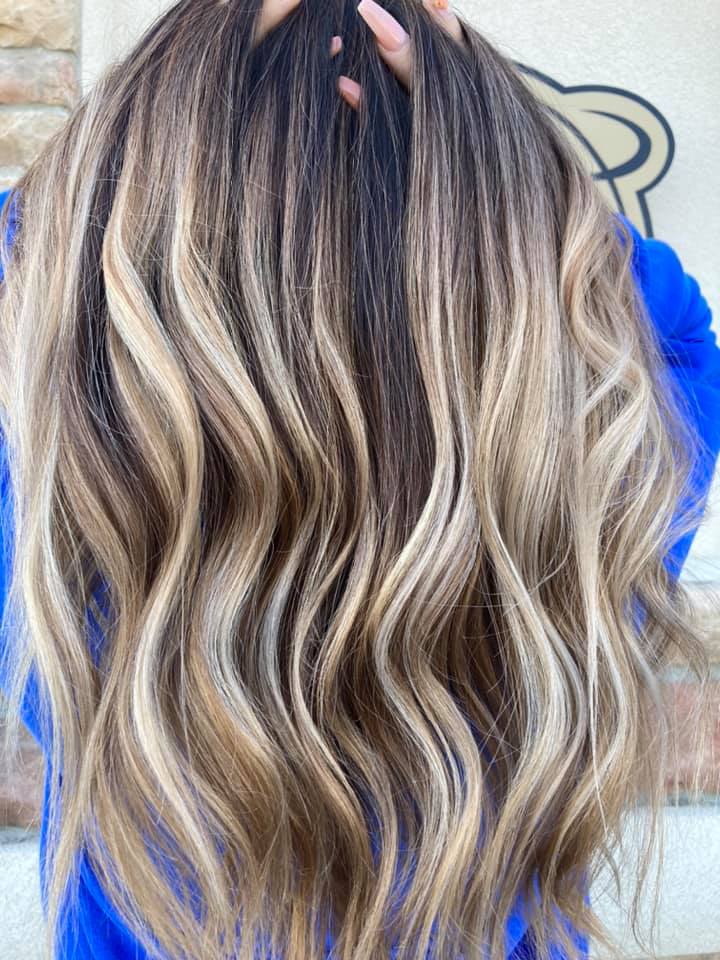 A woman with long wavy hair is wearing a blue sweater.