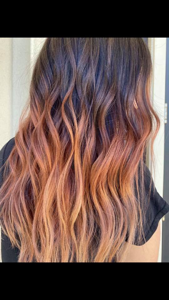A woman with long wavy hair is wearing a black shirt.