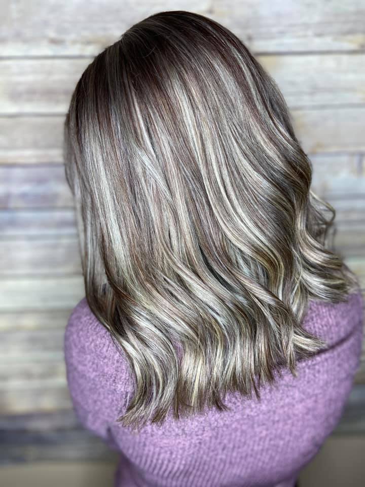 A woman with gray hair is wearing a purple sweater.