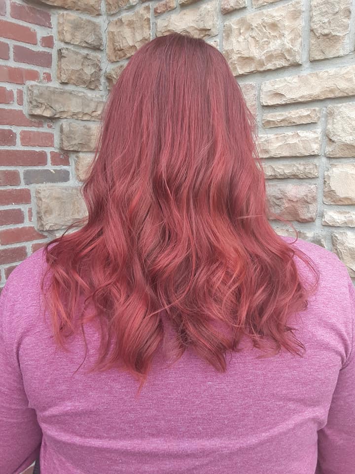 A woman with red hair is standing in front of a brick wall.