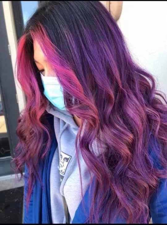 A woman with purple and pink hair is wearing a mask.