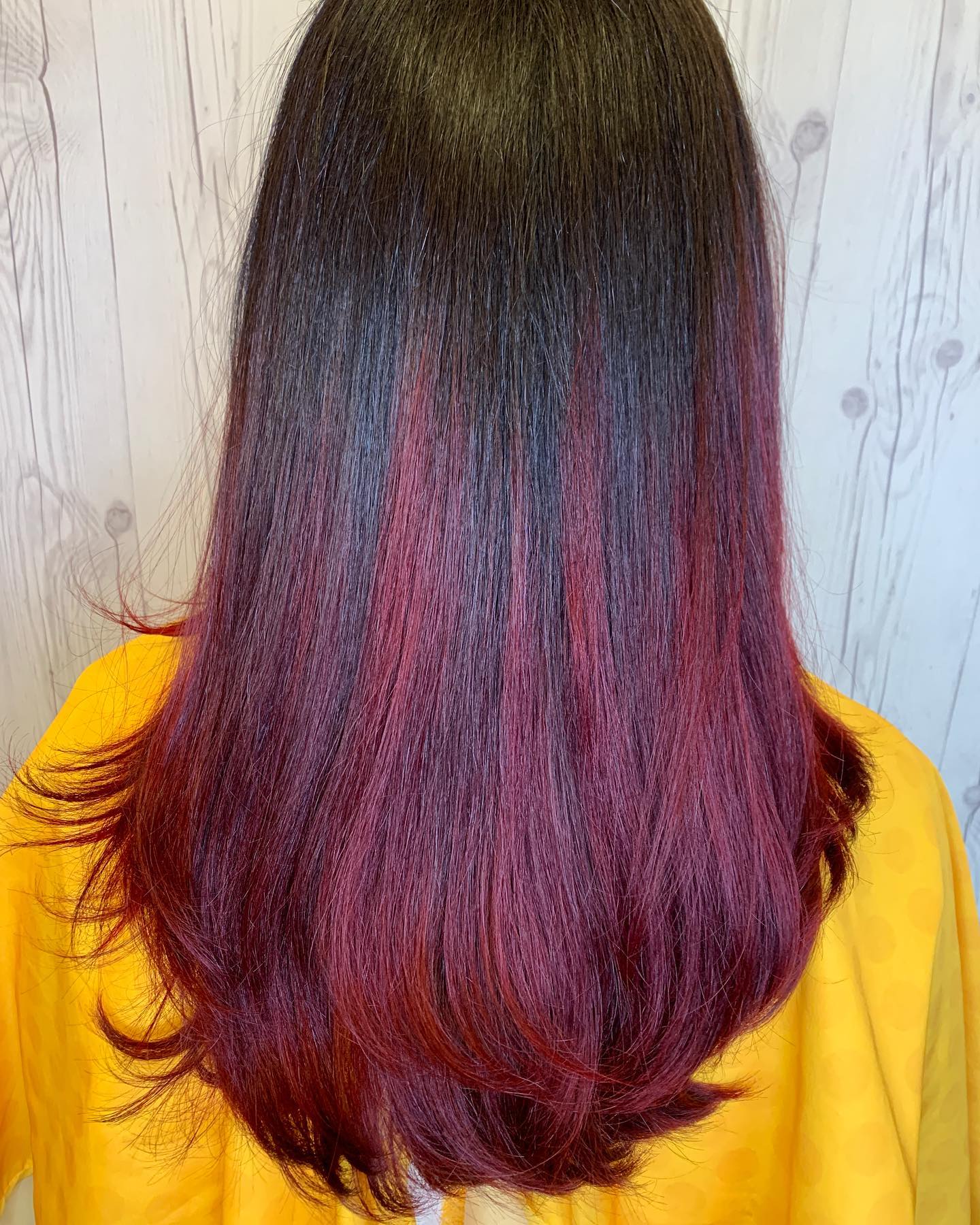 A woman with long red hair is wearing a yellow sweater.