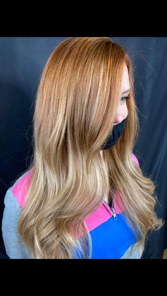 A woman with long blonde hair is wearing a mask.