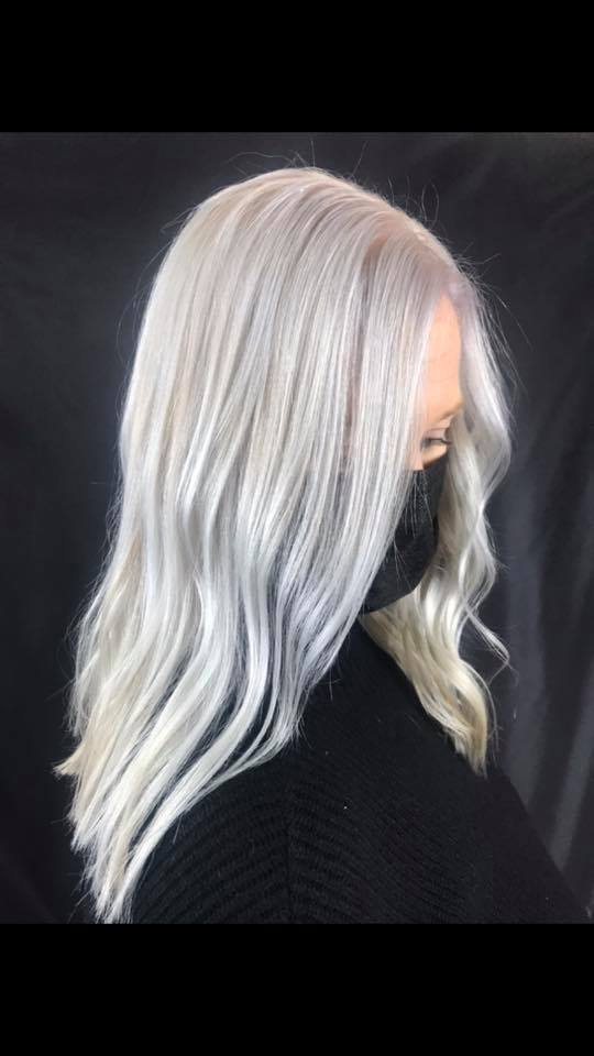 A woman with gray hair is wearing a black mask.