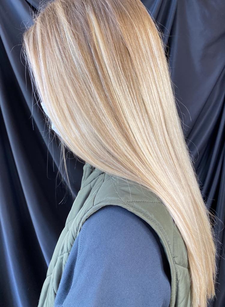 A woman with long blonde hair is wearing a green vest.
