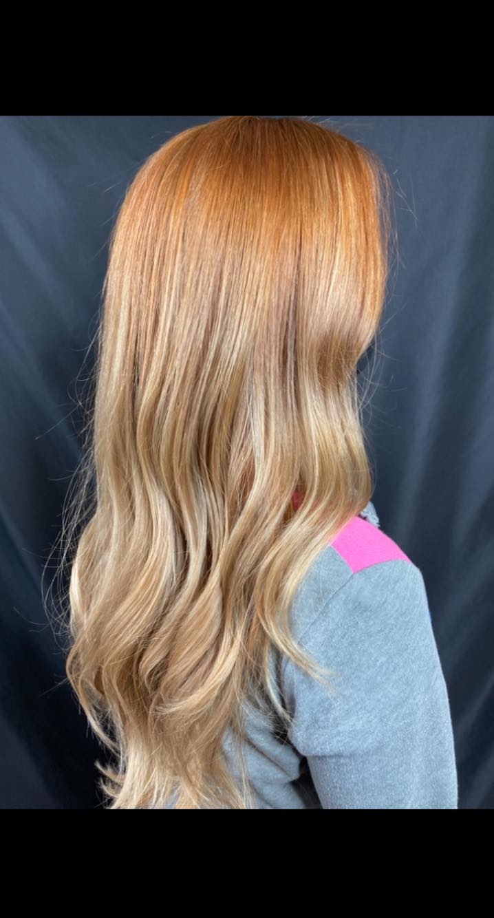 A woman with long blonde hair is wearing a gray sweater.