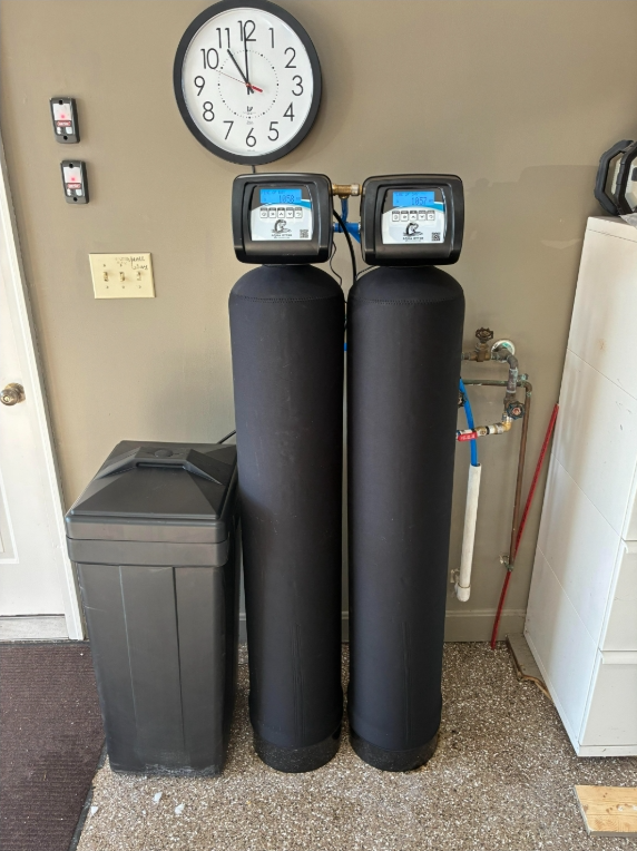 Water filtration and heater system in a basement setting. Tanks are various sizes and colors, with copper pipes.