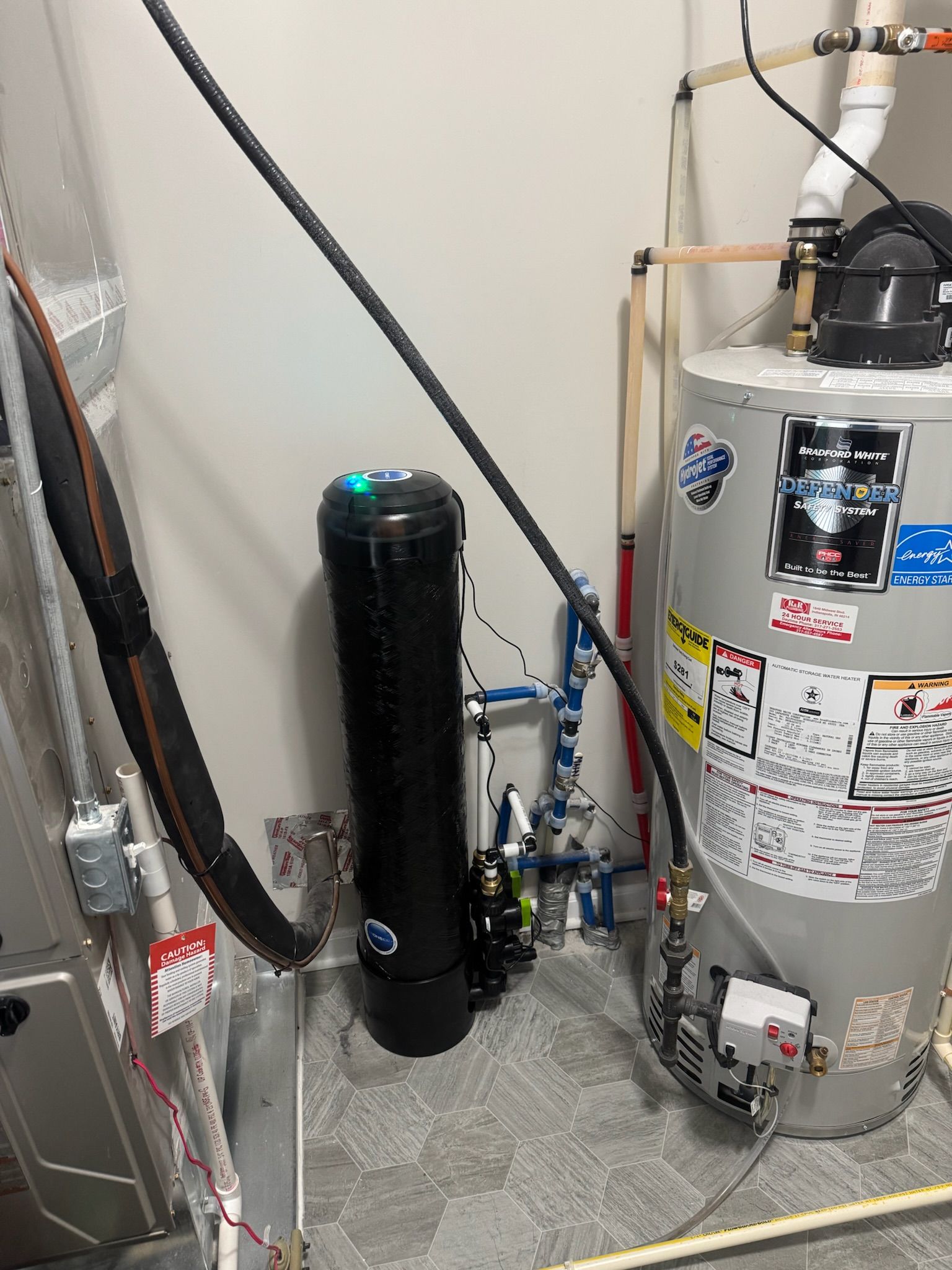 Water heater and water filtration system in a utility room; black filtration tank, grey heater.