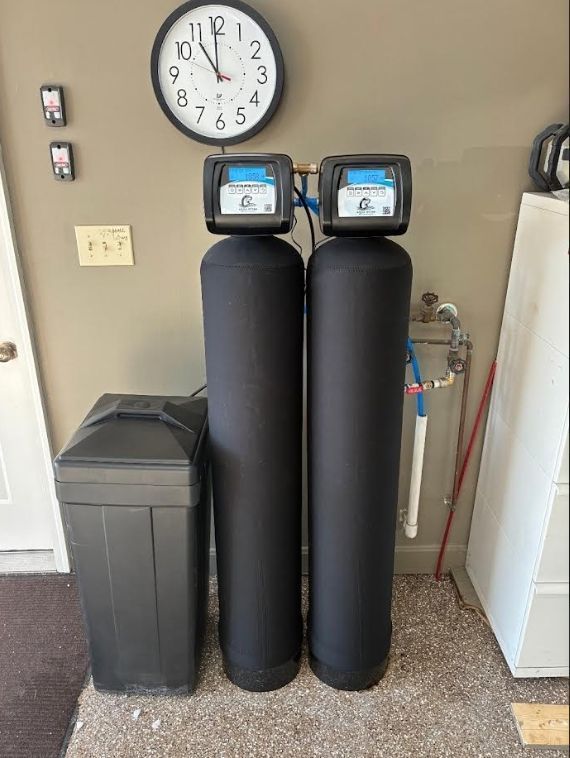Water softener system consisting of two black tanks, a salt container, and digital control panels.