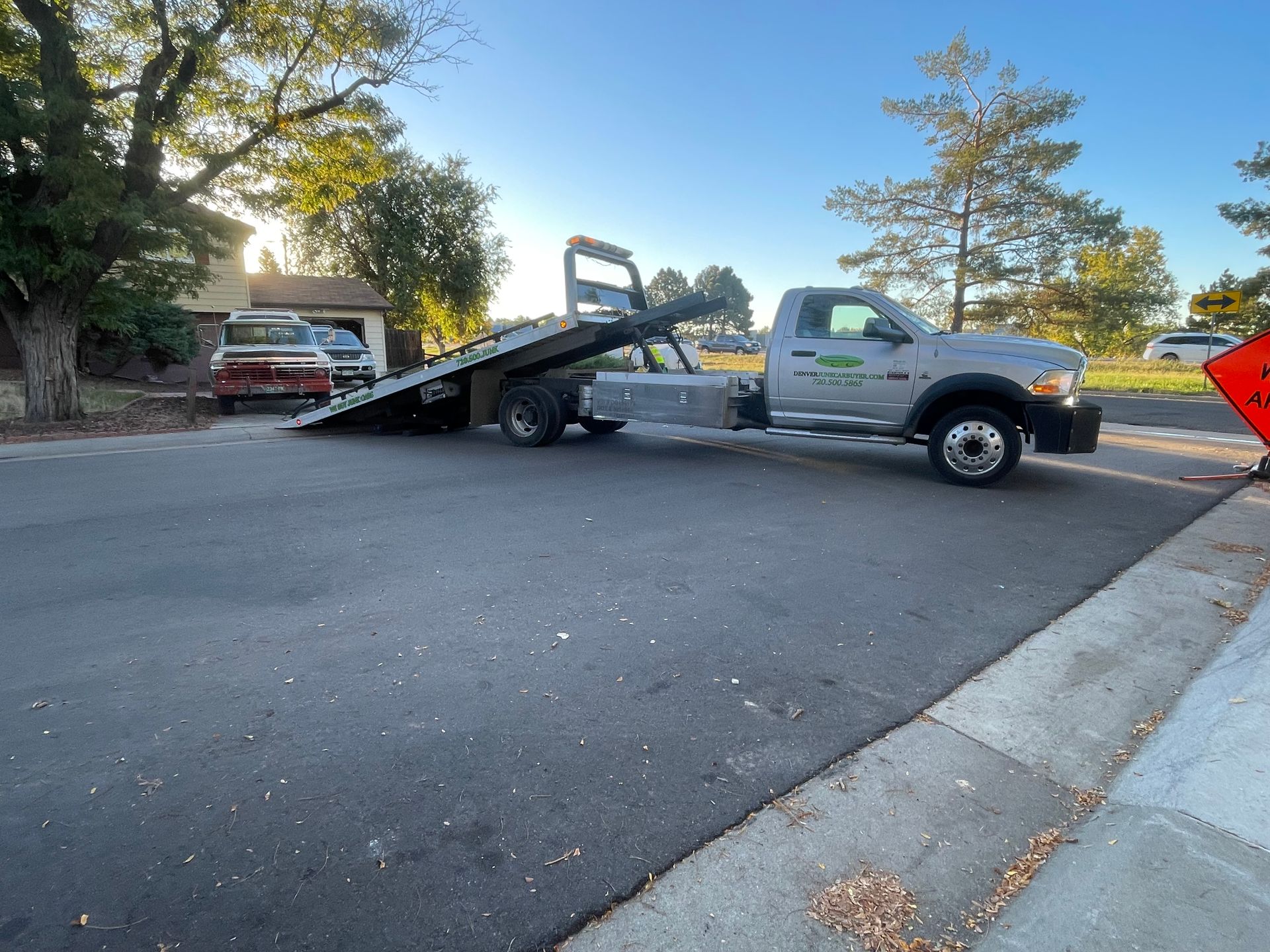 Tow truck loading a red car on a ramp in a street at dawn