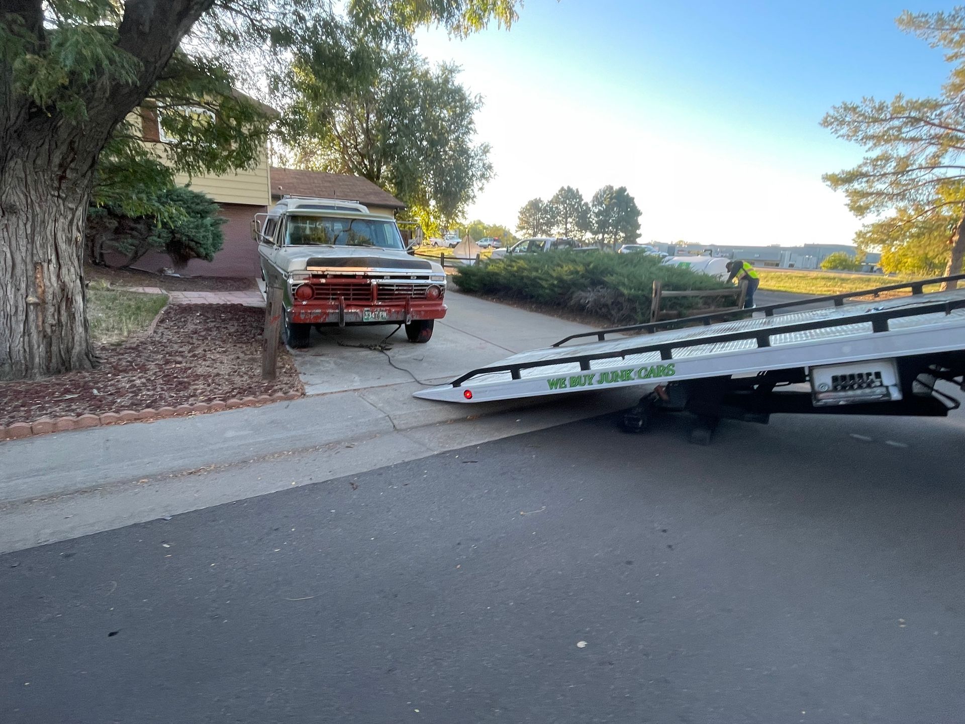 Tow truck loading a red pickup on a residential street at dusk