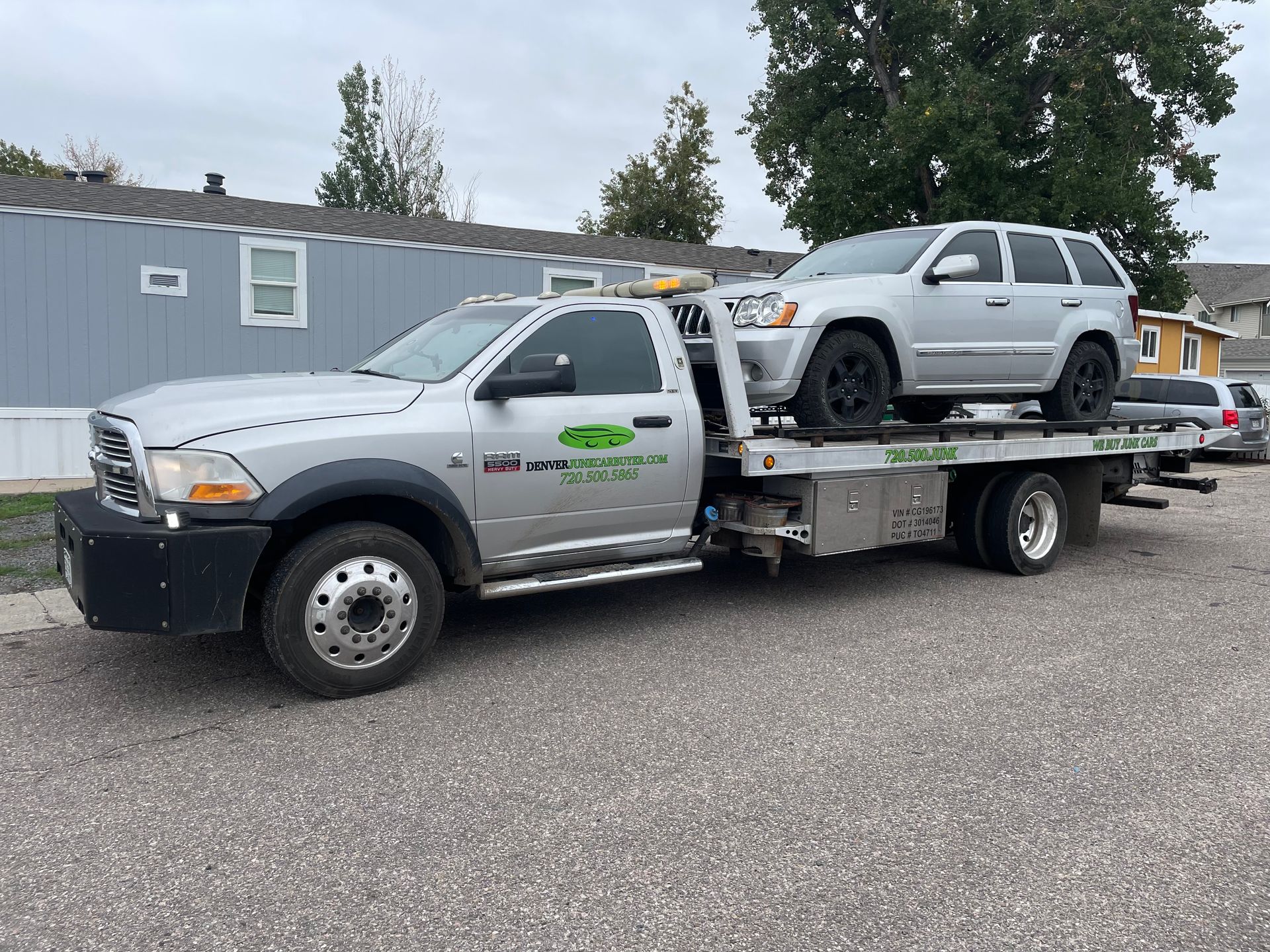 Tow truck hauling a silver SUV in a parking lot beside a gray building