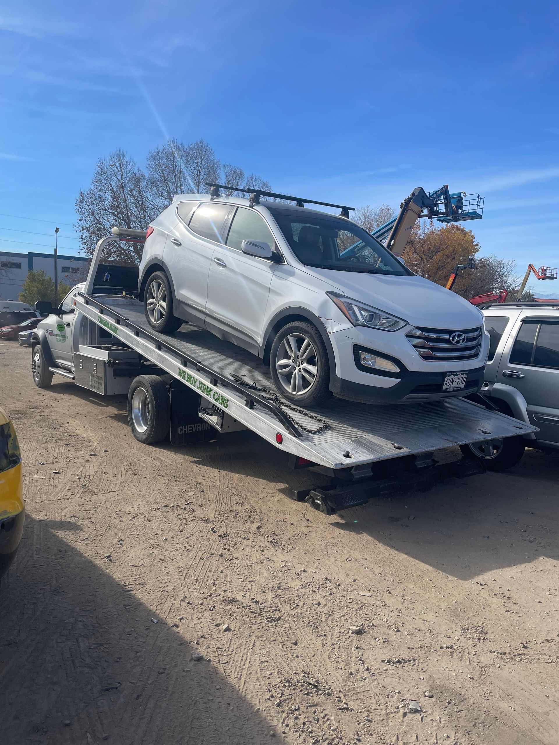 Silver SUV on a flatbed trailer in a sunny outdoor lot