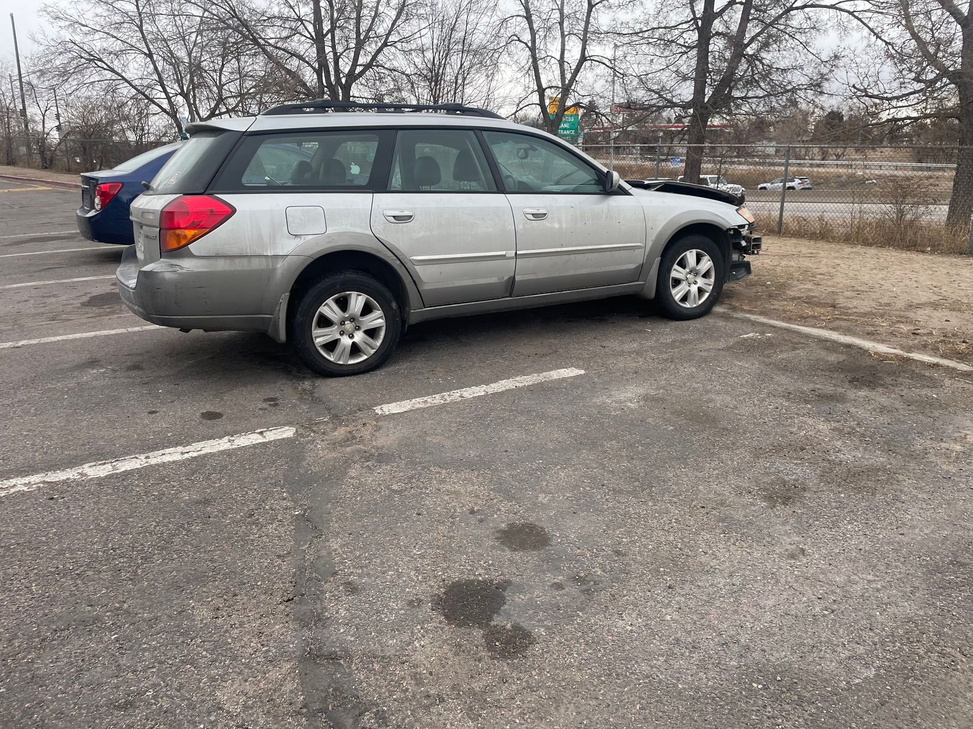 Silver SUV parked in a nearly empty lot with leafless trees in the background.