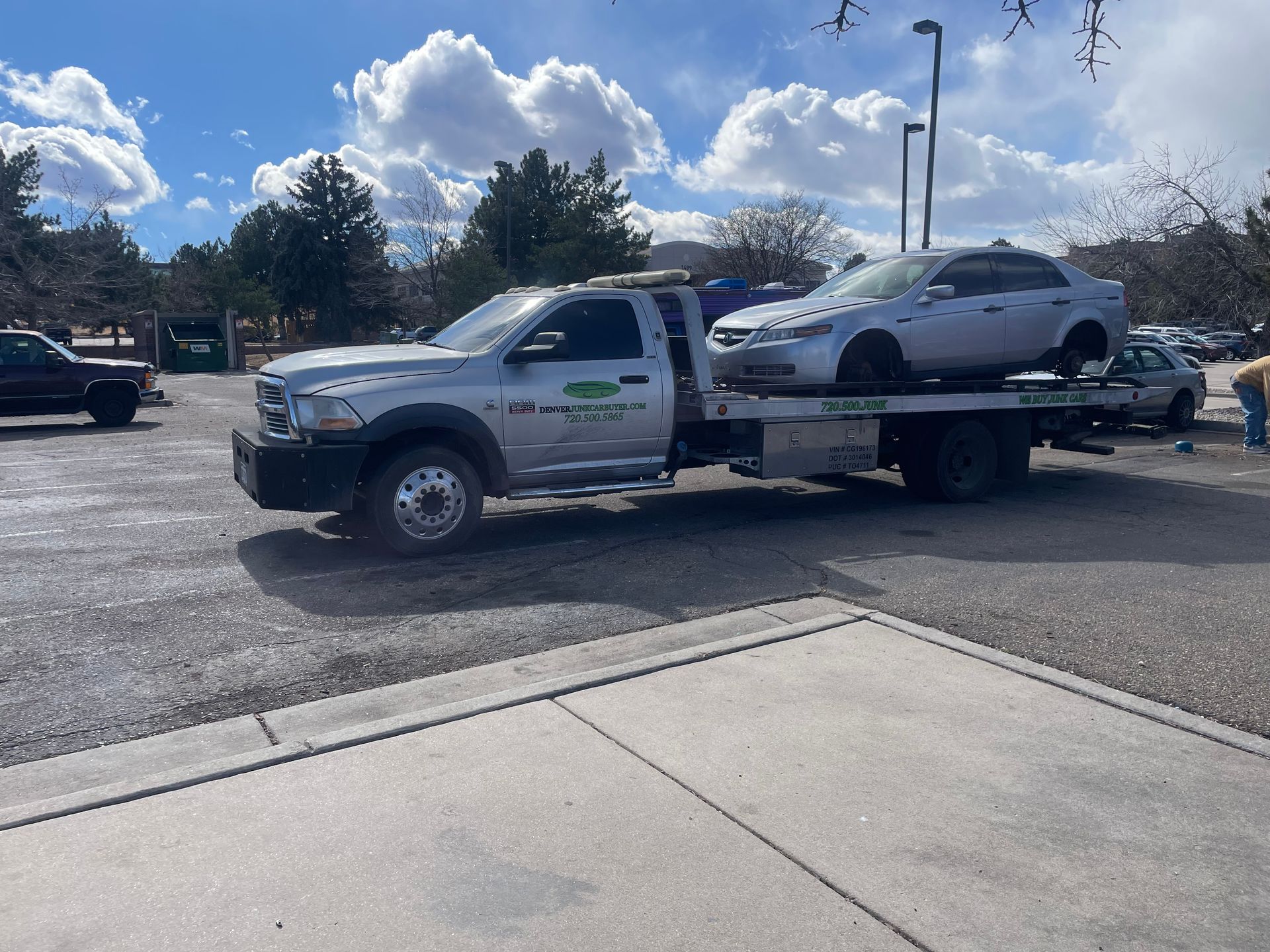 Tow truck carrying a white SUV in a parking lot under a cloudy sky