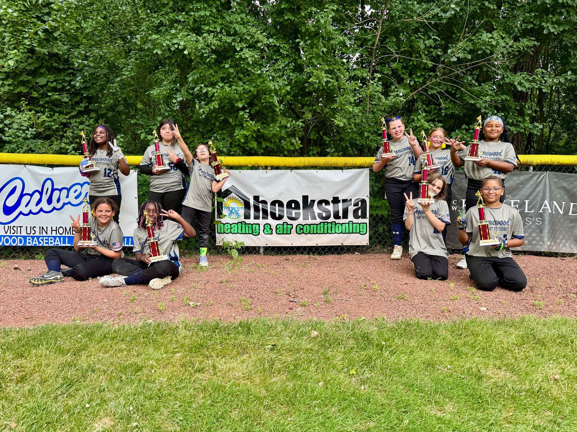 A group of young girls are posing for a picture on a baseball field.