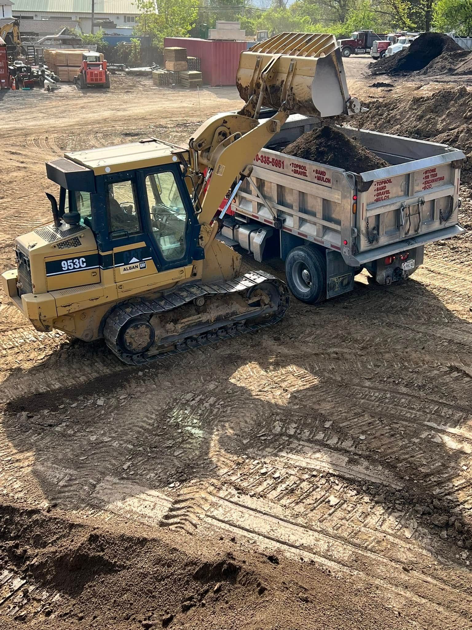 A bulldozer is loading dirt into a dump truck.