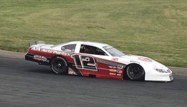 A race car with the number 12 on it is driving down a track.