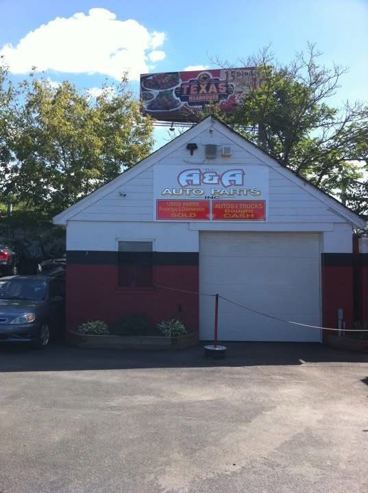 A car is parked in front of a building that says aaa