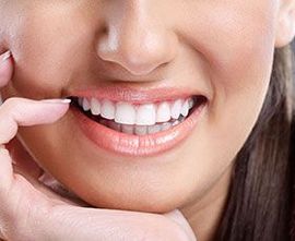 Close-up of a smiling mouth with white teeth being pointed at by a finger.