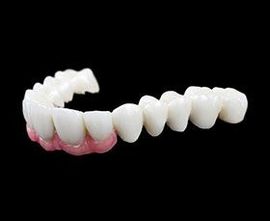White denture teeth with pink gum base on a black background.