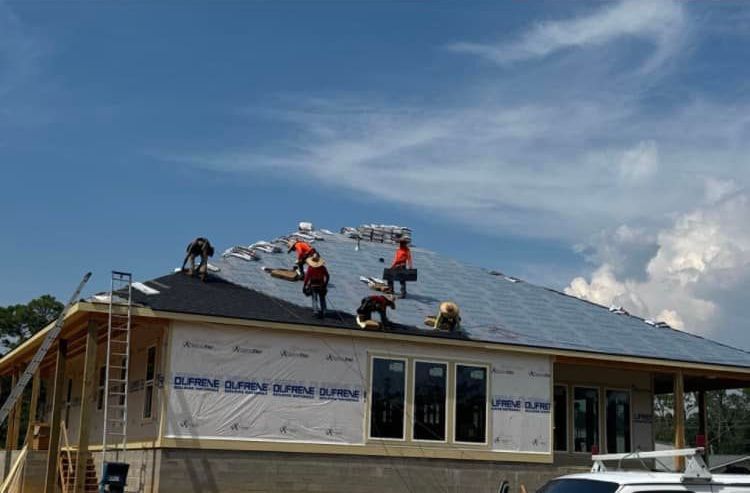 A group of men are working on the roof of a house.