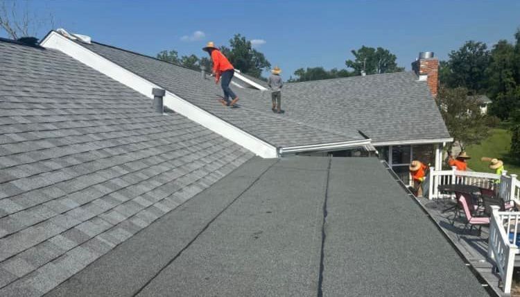 A group of men are working on a roof of a house.