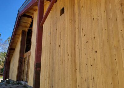 Wooden building exterior with vertical wood siding and red support beams.