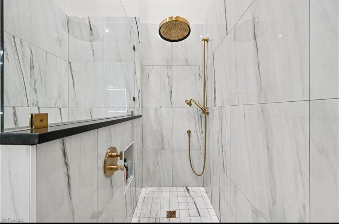 A bathroom with marble tiles and a walk in shower.